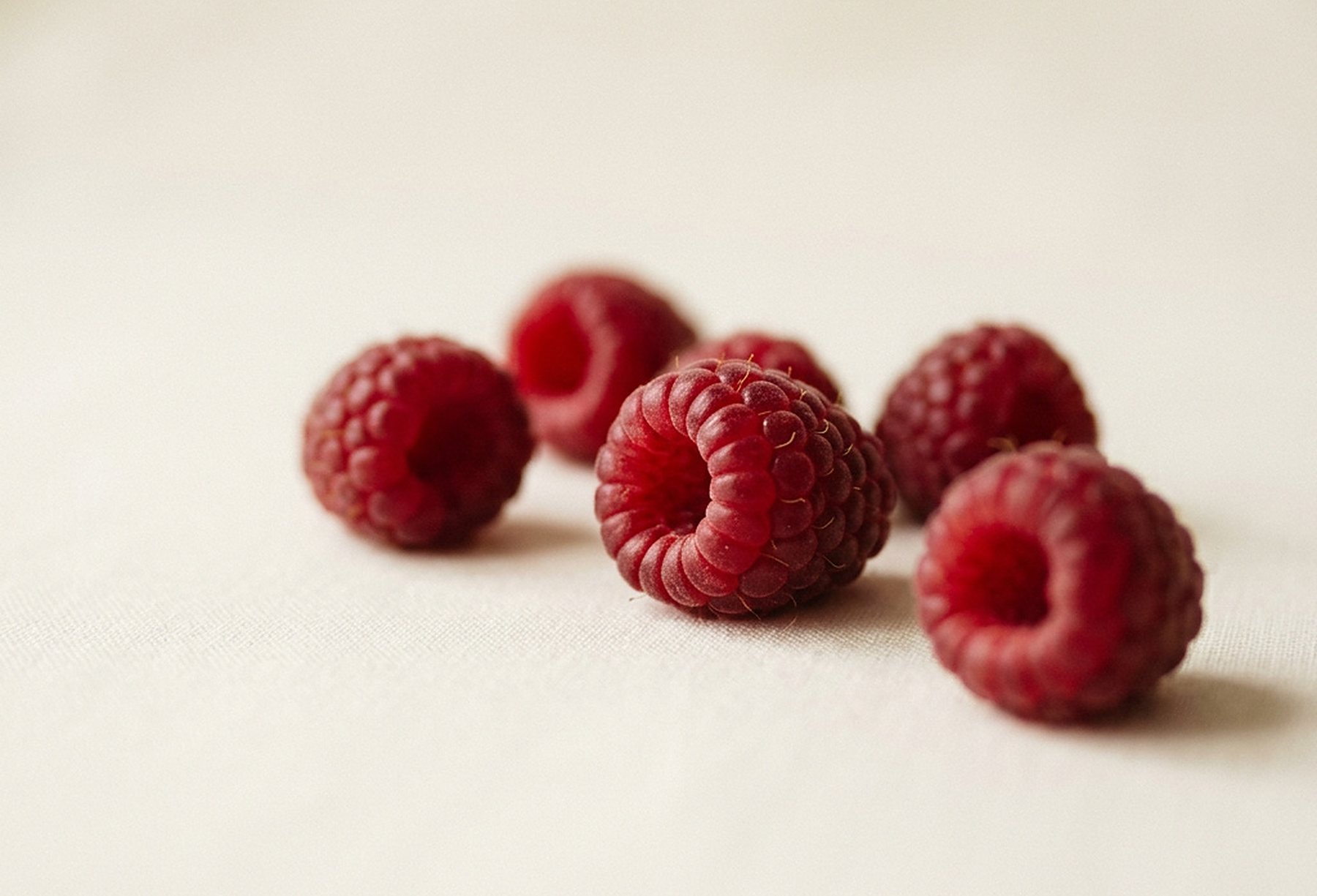 Fresh raspberries on a warm off-white surface